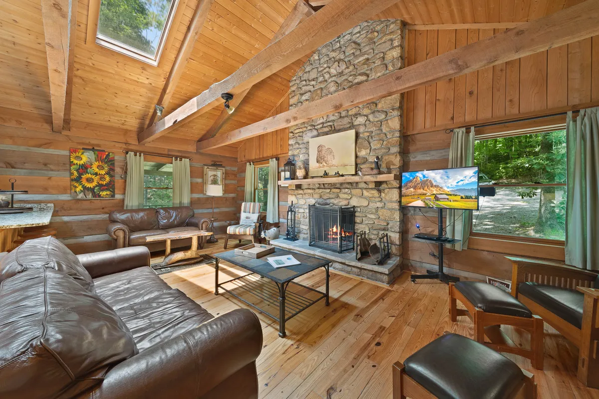 A cozy interior setting showcases a stone fireplace, wooden beams, a leather sofa, and tasteful wall art. The room is warmly lit and inviting, capturing the essence of family gatherings for board games, storytelling, or warming up after outdoor adventures.