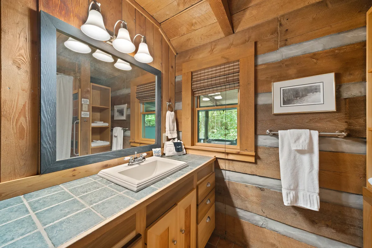 This bathroom image features a stylish combination of a sink, mirror, wooden cabinetry, and windows letting in morning light. The overall mood is fresh and inviting, perfect for relaxation and self-care.
