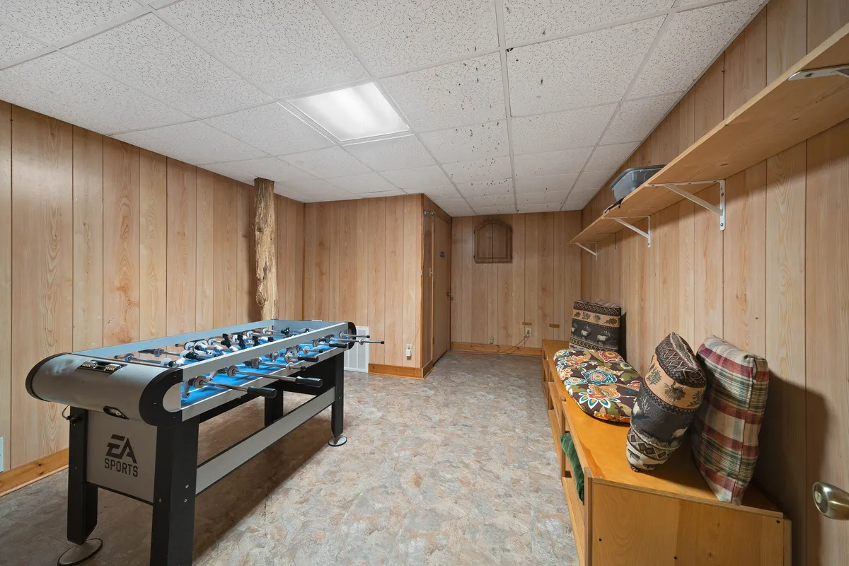 A cozy area with a foosball table as the centerpiece, flanked by a wooden shelf and cushioned seating. The scene radiates a fun and inviting mood, ideal for friendly tournaments and lively group gatherings.