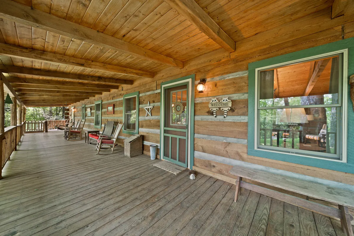 A welcoming wooden porch with rocking chairs, decorative elements like a star and welcome sign, and a view toward the cabin's entrance. The setup suggests a cozy spot to unwind, enjoy the view, and spend time together.